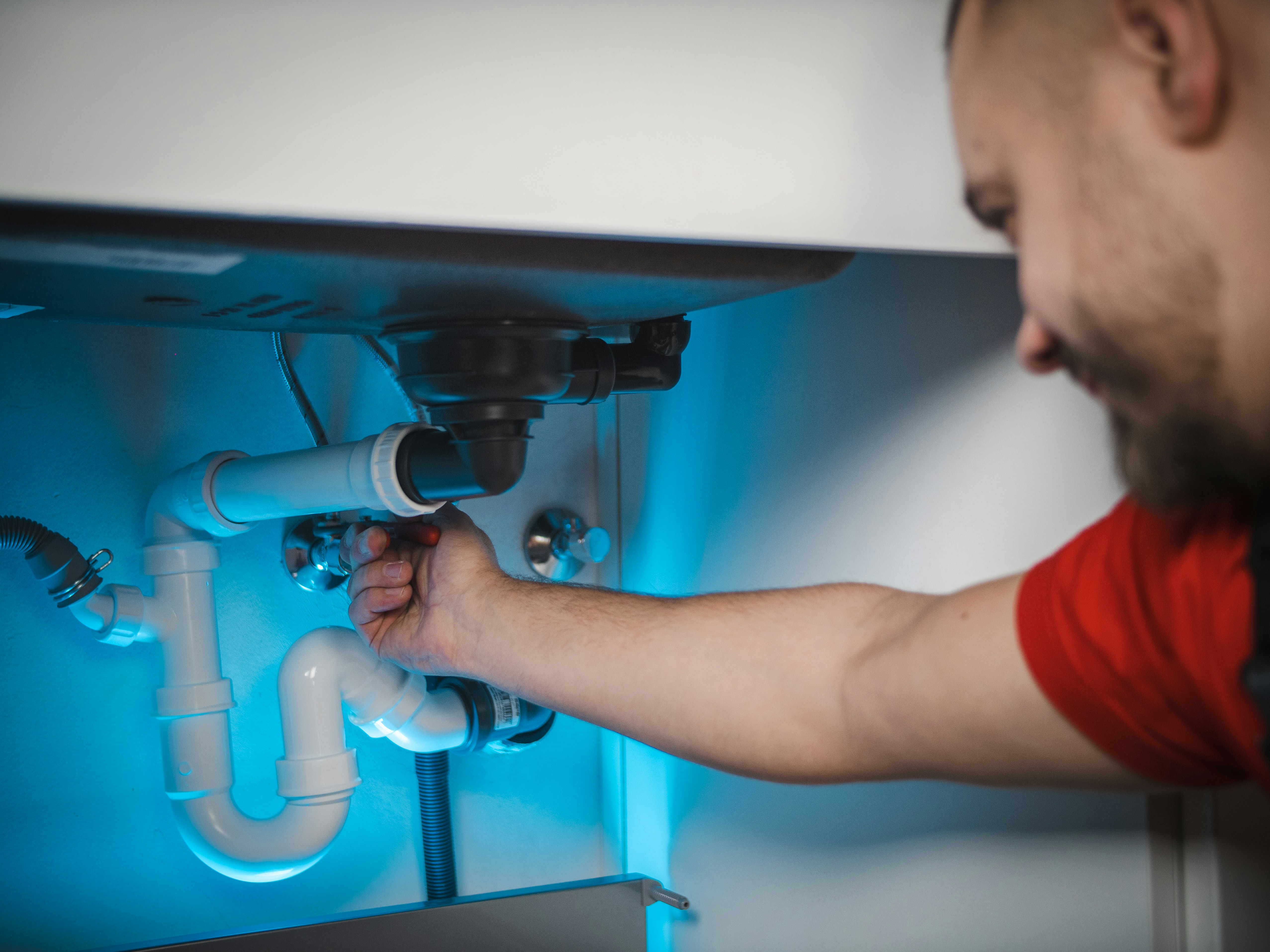 A plumber reaching in to adjust the trap under a sink