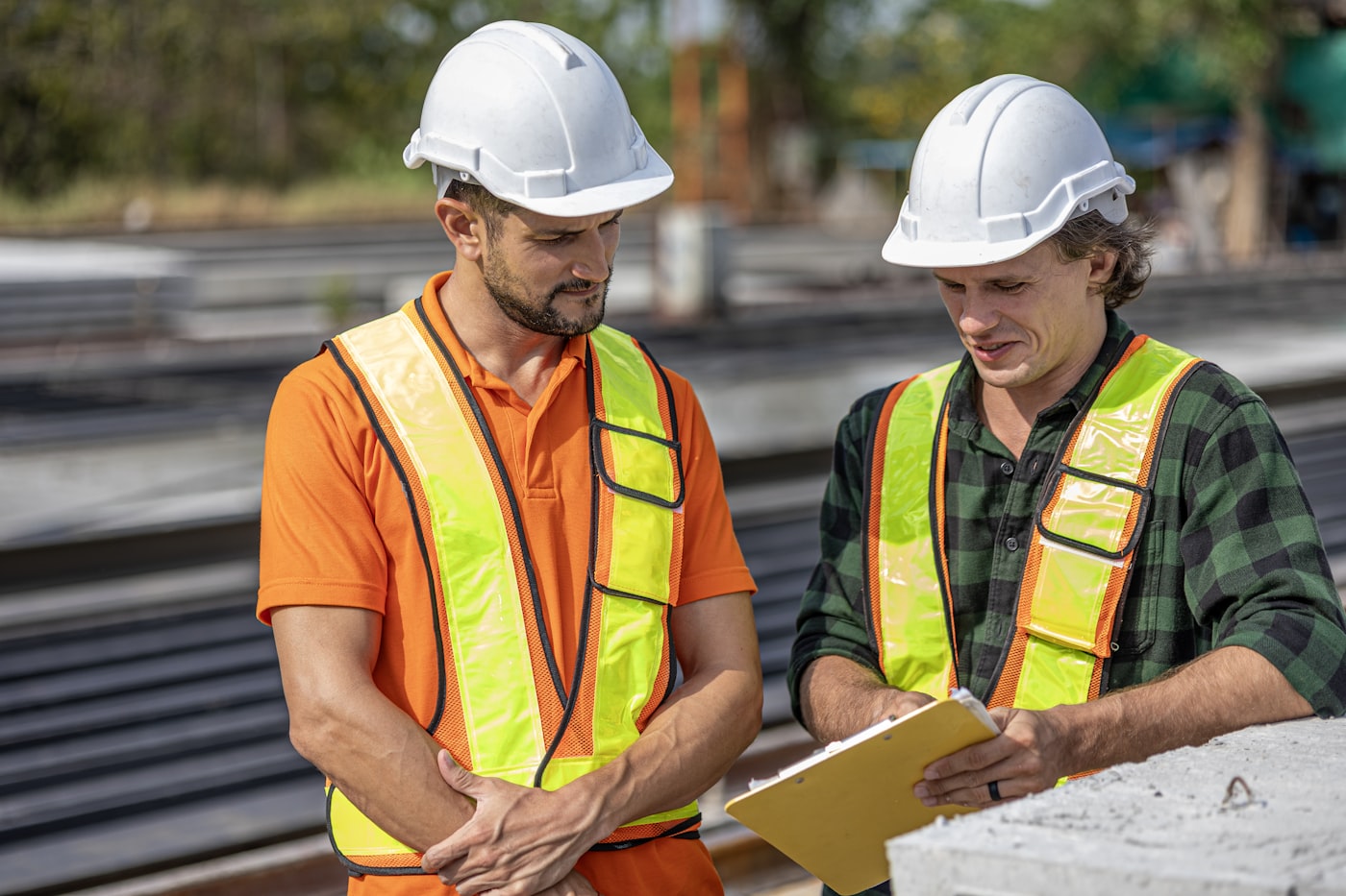 Two construction workers in hi-vis vests reviewing plans together