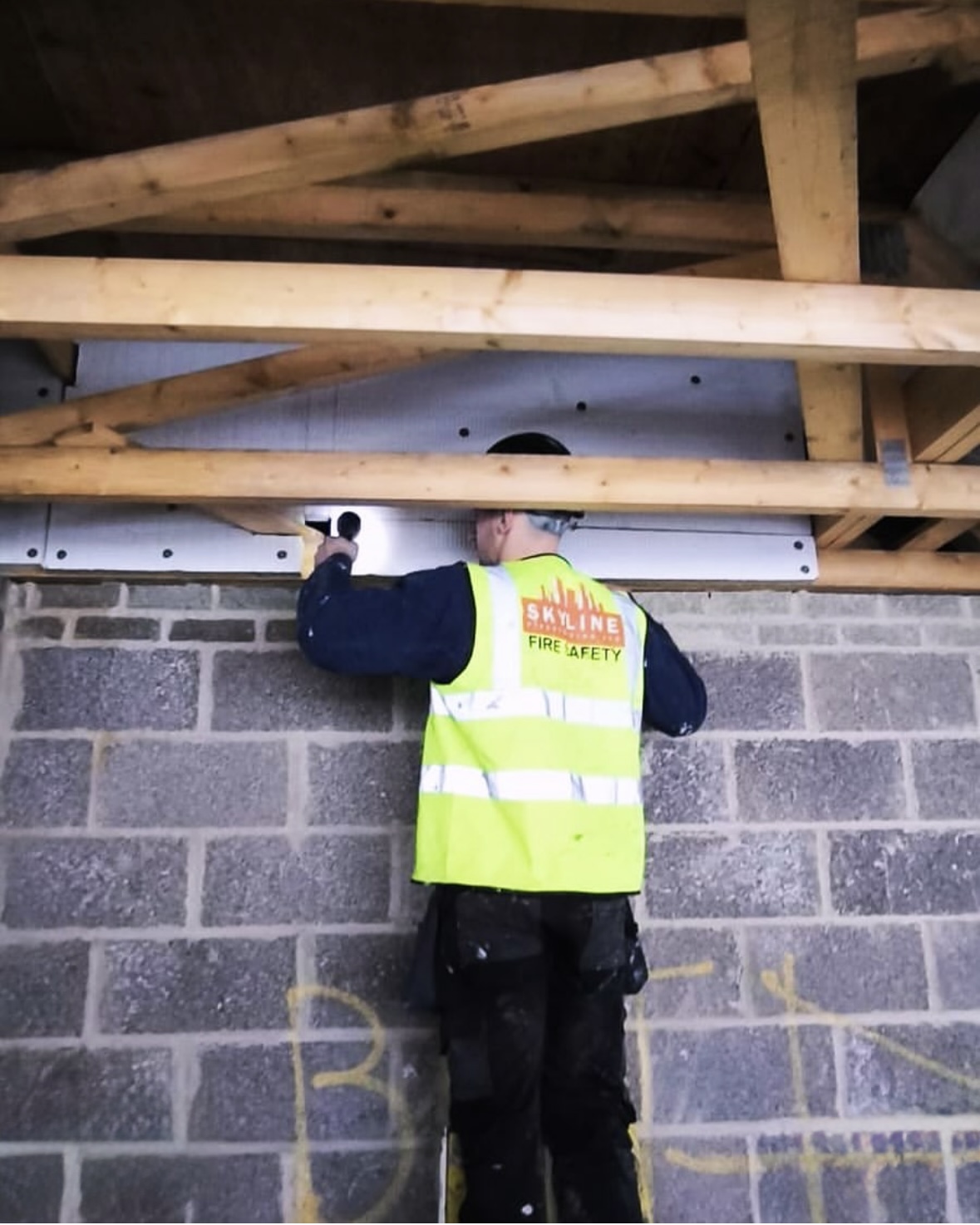 Skyline installer checking a sealed penetration under roof trusses by torchlight