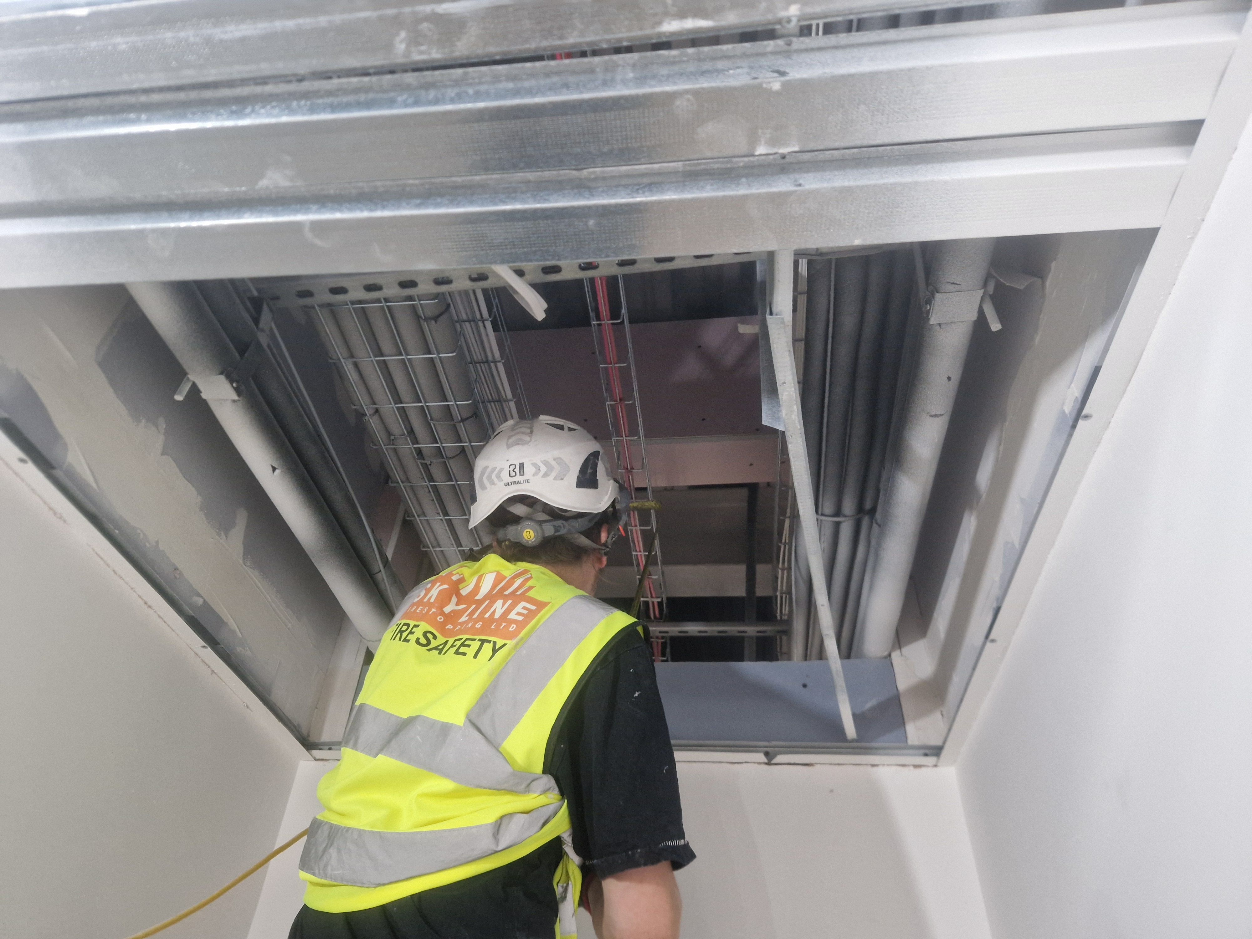 The B3 compartmentation duties of Approved Document B, delivered on site: a Skyline operative inspecting the fire-rated compartment line above a ceiling where the seal is built and proven
