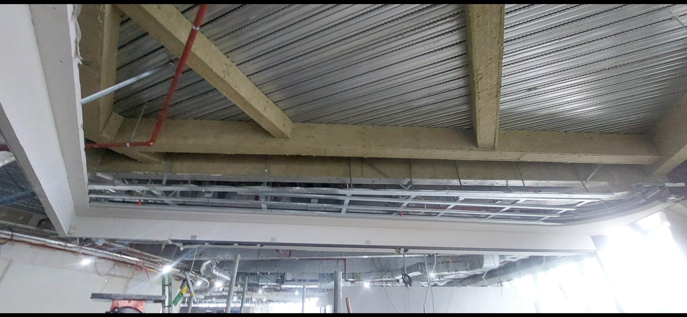 Fire rated materials in place: fire rated board installed between a beam and a metal deck, holding its rating only as part of the tested system it was installed as