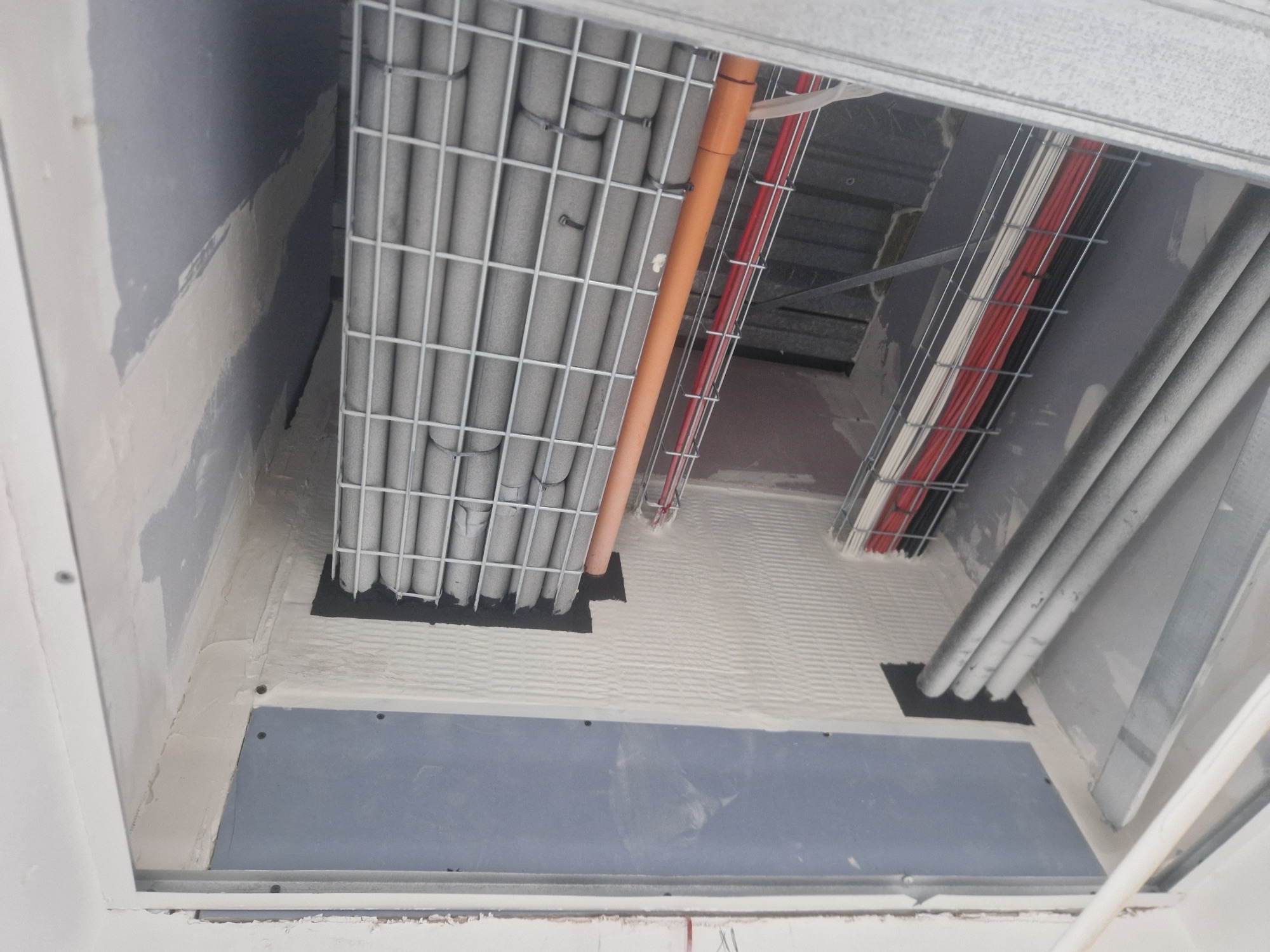 Firestopped service penetrations through a floor slab inside a riser: the compartment line a fire strategy draws, kept where the services cross it