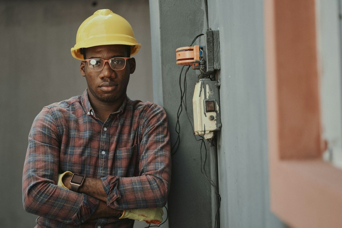 A contractor in a hard hat standing on his job site with his arms crossed