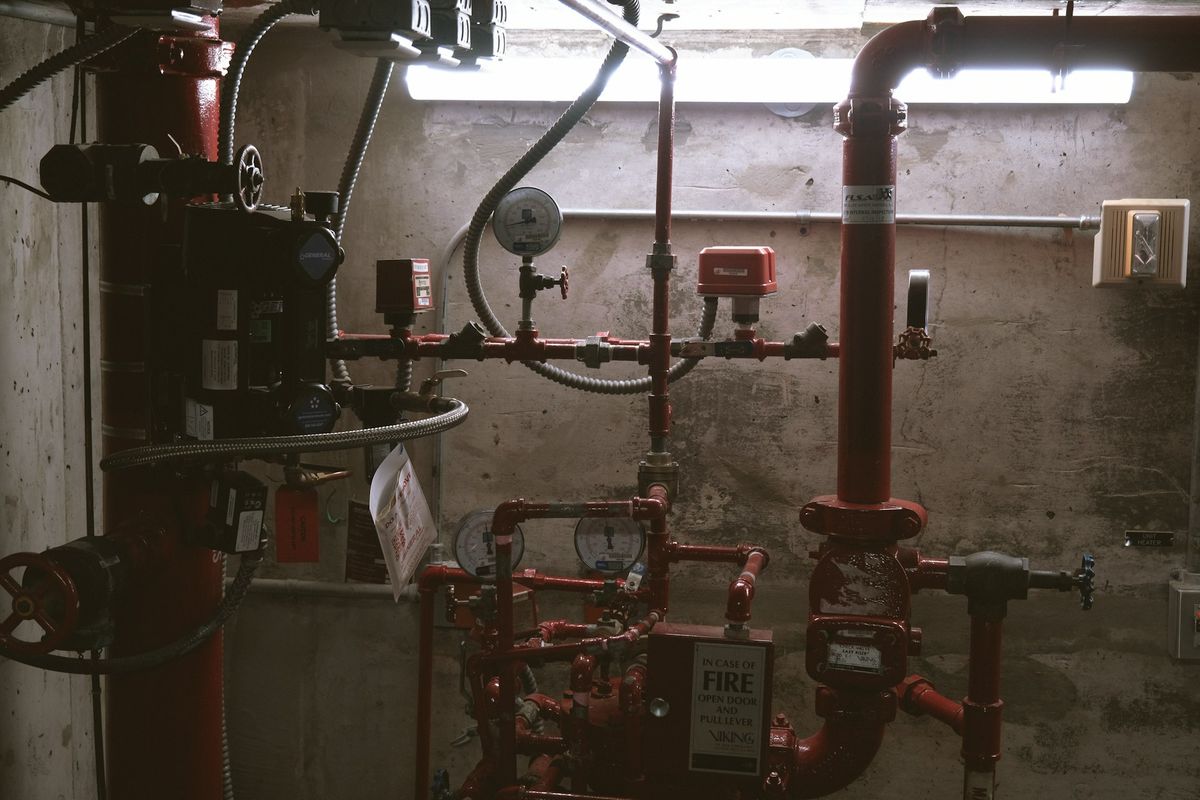 Fire sprinkler riser and alarm valves with an inspection tag in a building plant room