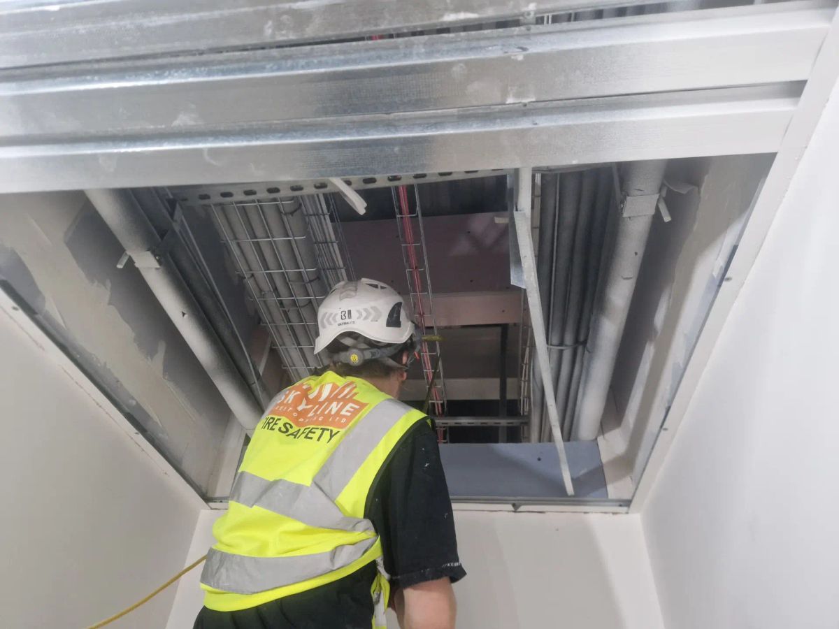 A Skyline operative inspecting the fire-rated compartment line above a ceiling
